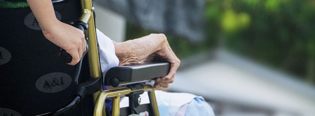 Vista parcial de una silla de ruedas llevando a una persona mayor