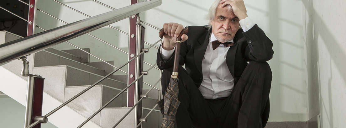Hombre mayor con gesto apesadumbrado sentado en una escalera