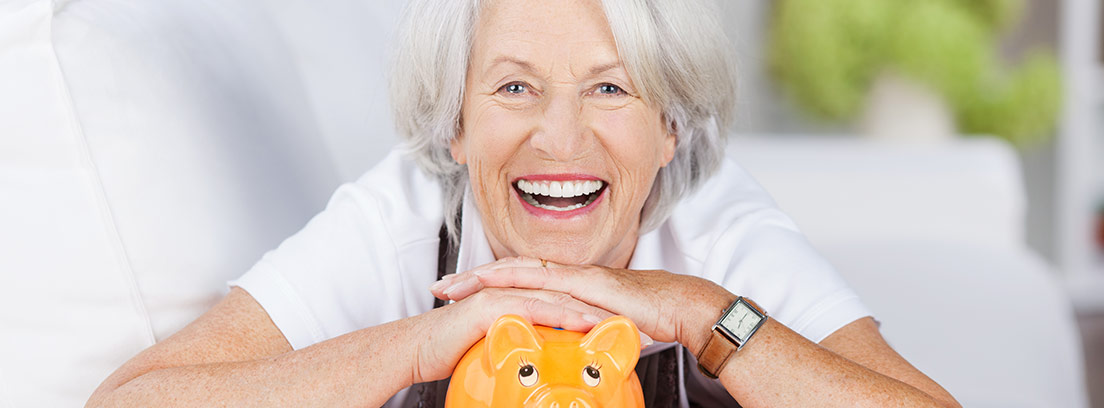 Mujer sonriente apoyada en una hucha de color naranja