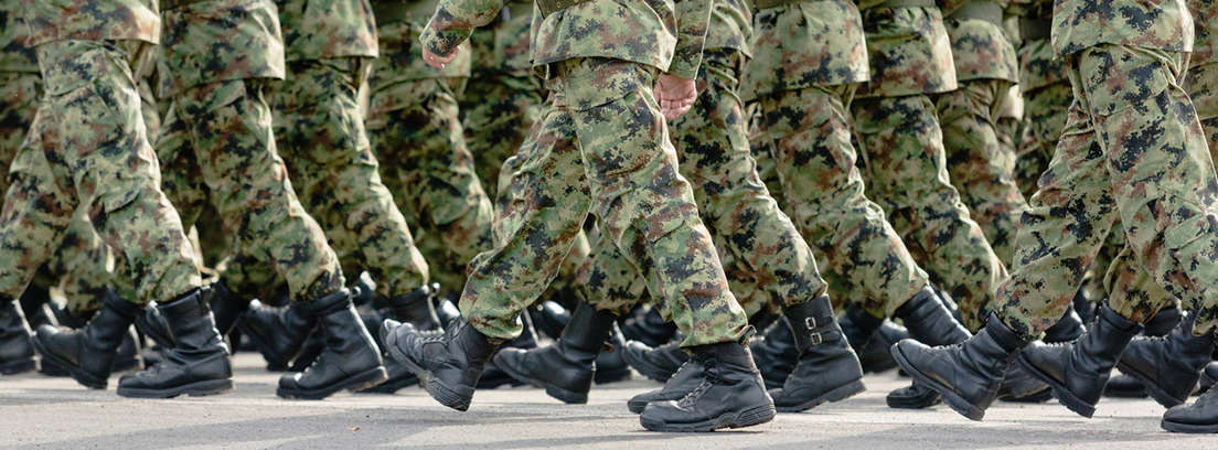 Fila de personas con manos sujetas a la espalda y vestidos con uniforme militar