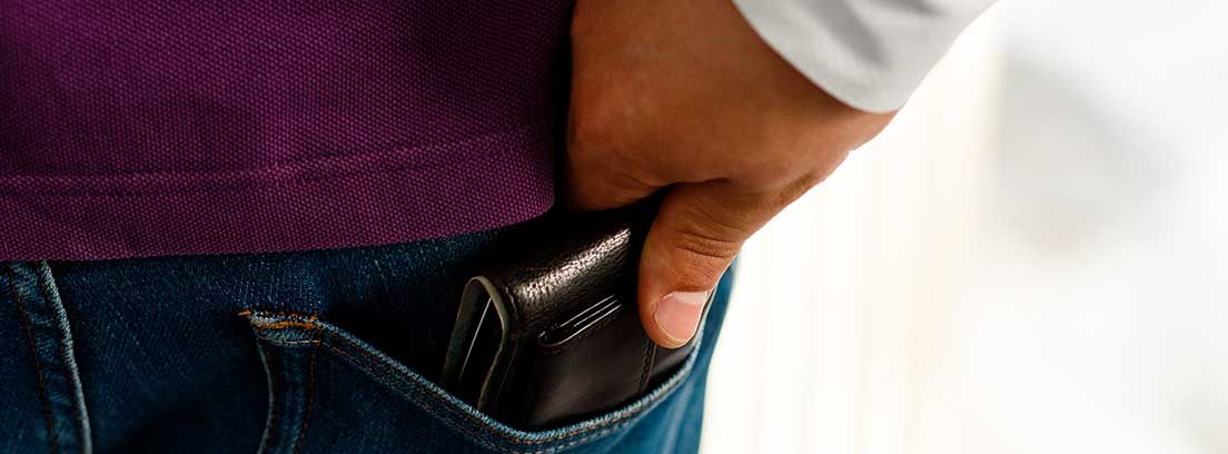 Una mano roba la cartera del bolsillo trasero de un pantalón vaquero
