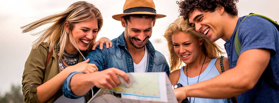 Un grupo de jóvenes turistas revisan un mapa de manera sonriente