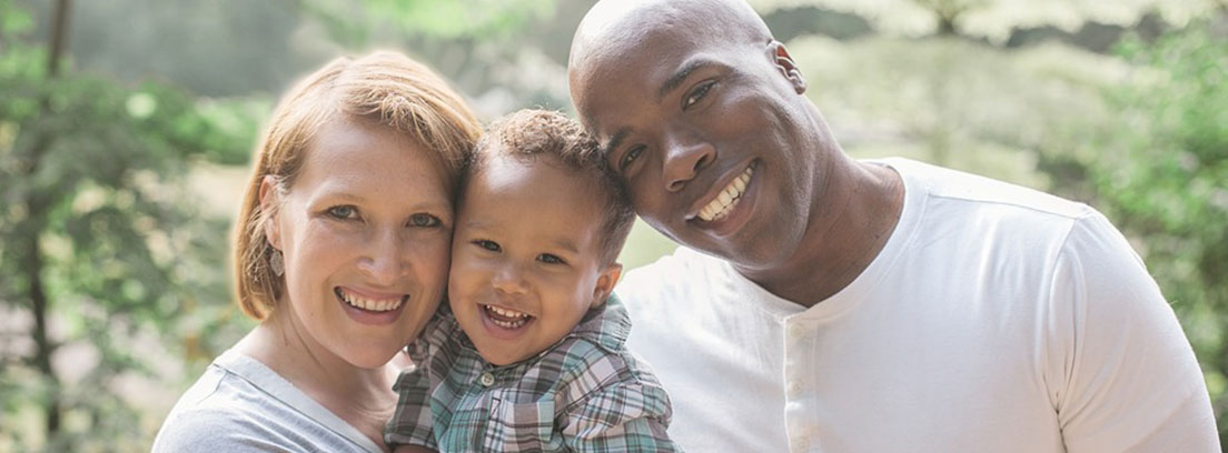 Familia interracial. La madre sostiene al bebé en brazos. Todos sonríen