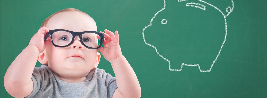 Bebé con gafas de pasta delante de una pizarra con una hucha pintada