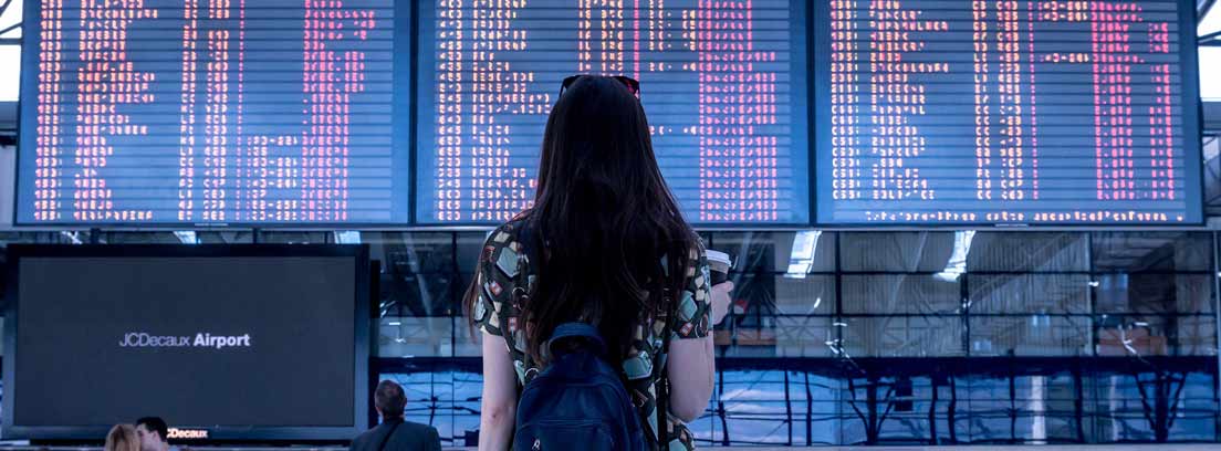 Mujer delante de un panel luminoso informativos sobre destinos de viaje