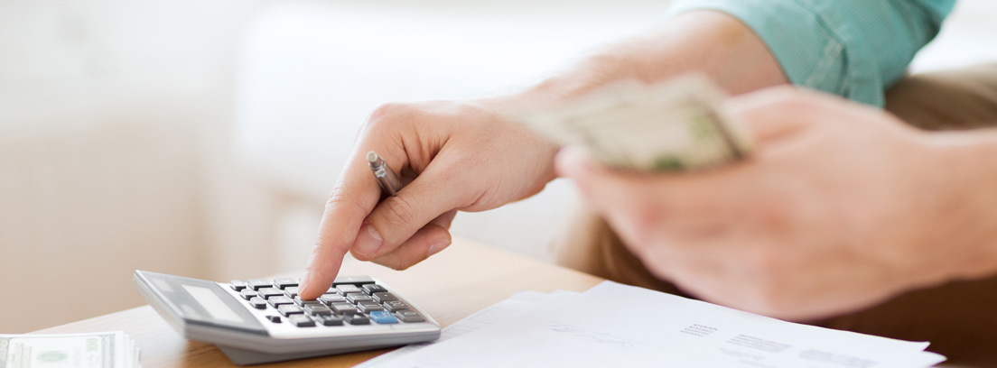 Vista de una manos con billetes y una calculadora calculando su aportación máxima al plan de pensiones