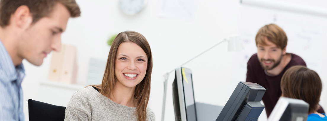 Personas sonrientes junto a ordenadores