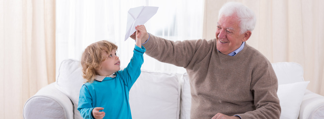 Niño y persona mayor jugando con aviones de papel