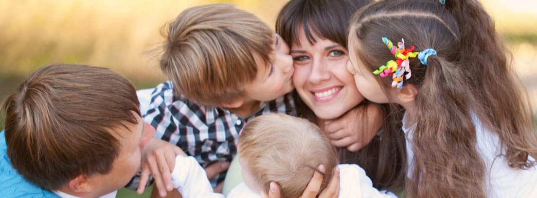 Familia numerosa con tres hijos dando besos a su madre