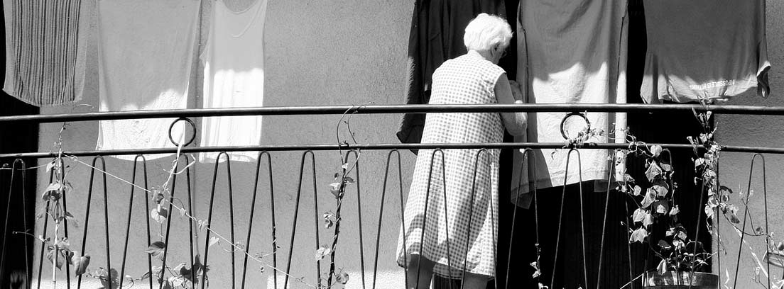 Mujer mayor en un balcón tendiendo la ropa