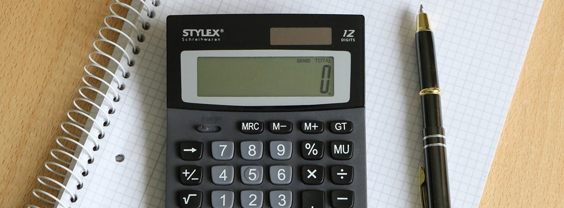 Calculadora sobre cuaderno de cuadros y junto a bolígrafo