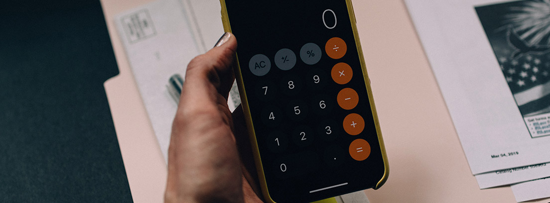 Mano sujeta una calculadora con pantalla con el número cero y sobre papeles