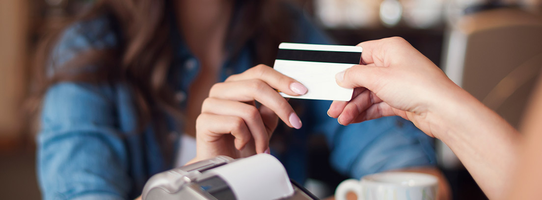 Una mujer paga un café con tarjeta de crédito