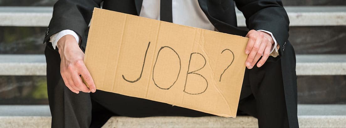 Hombre con traje sujetando un cartel en el que puede leerse: “Job?”