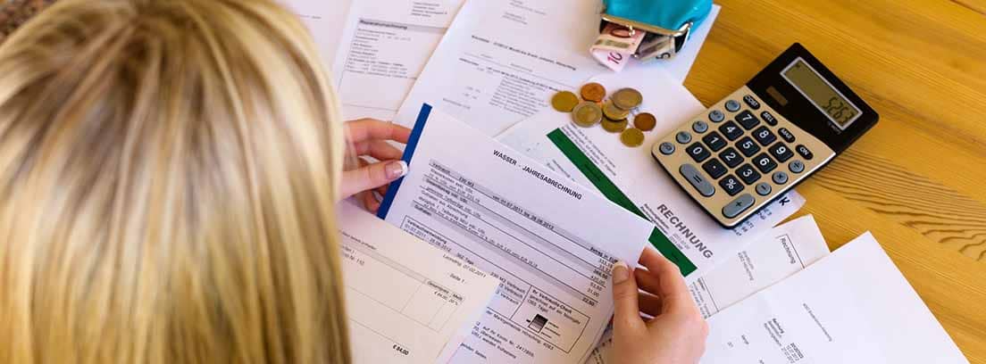 Mujer revisando facturas con una calculadora y un monedero