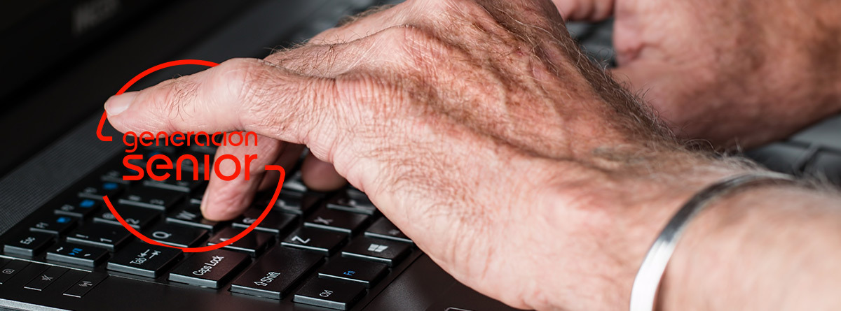 Manos de persona mayor sobre el teclado de un ordenador