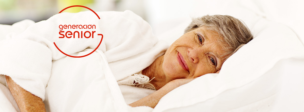 Mujer mayor sonriente tumbada en una cama