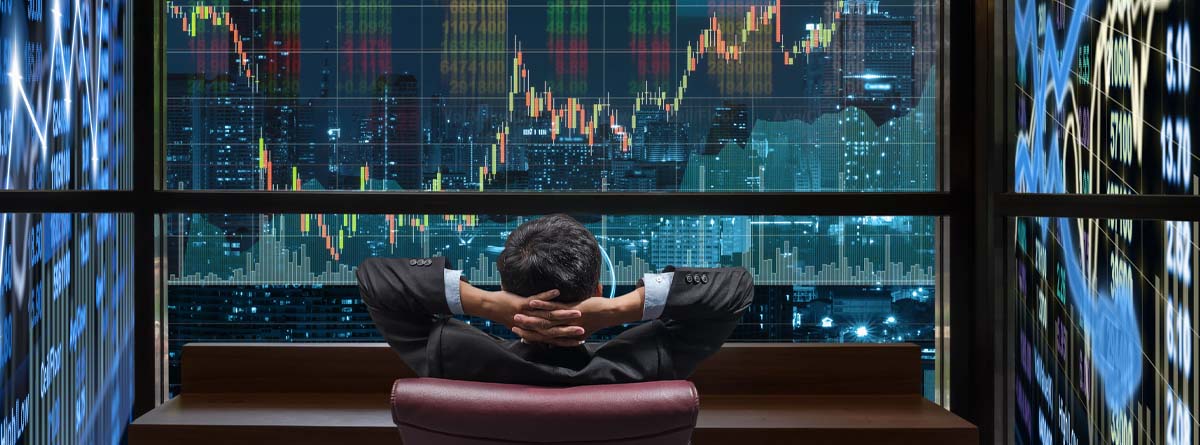 Hombre de negocios sentado mirando una pantalla con el mercado de valores