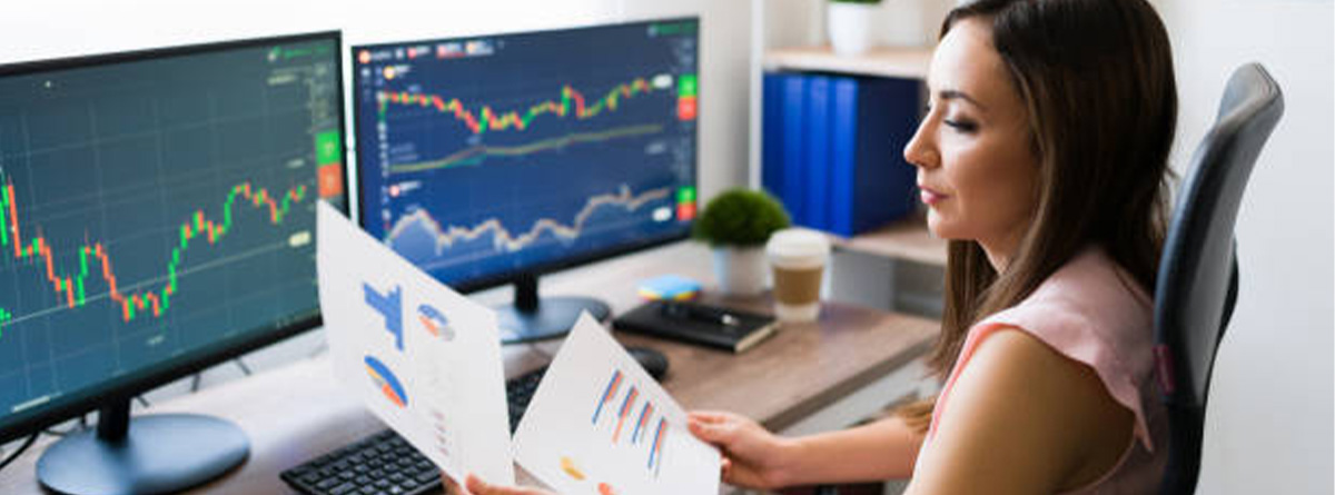 Mujer trader con dos pantallas con gráficos para operar en los mercados financieros
