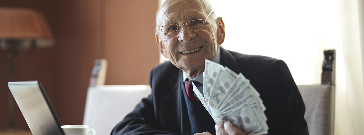 Hombre con dinero en la mano frente a un portátil